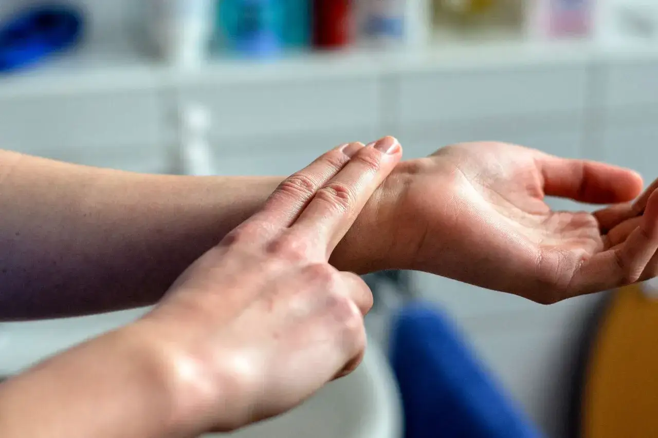 Dwie dłonie, jedna sprawdza puls na drugiej. Tętno spoczynkowe 55, idealne dla sportowca.
