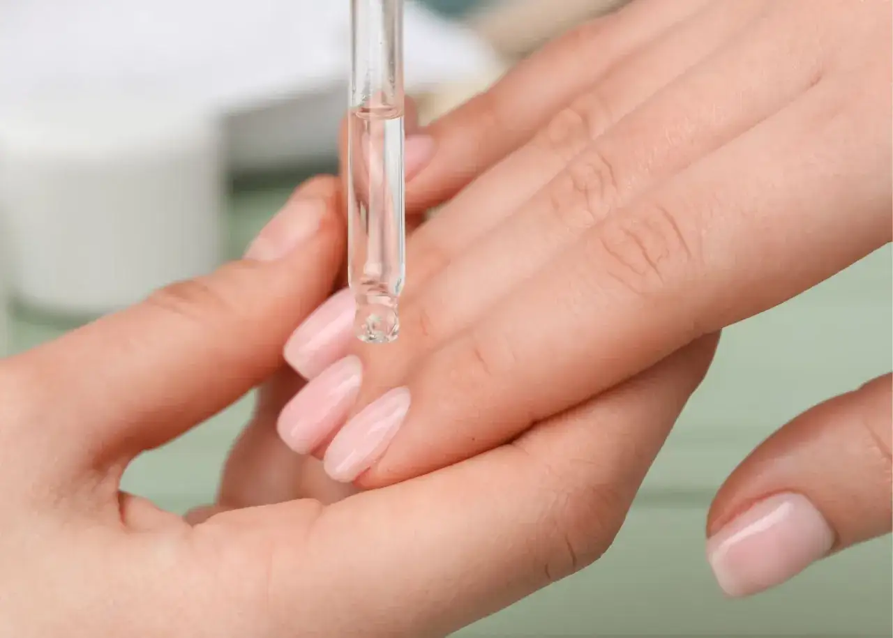 Goutte d'huile sur les cuticules des ongles pour une hydratation parfaite.