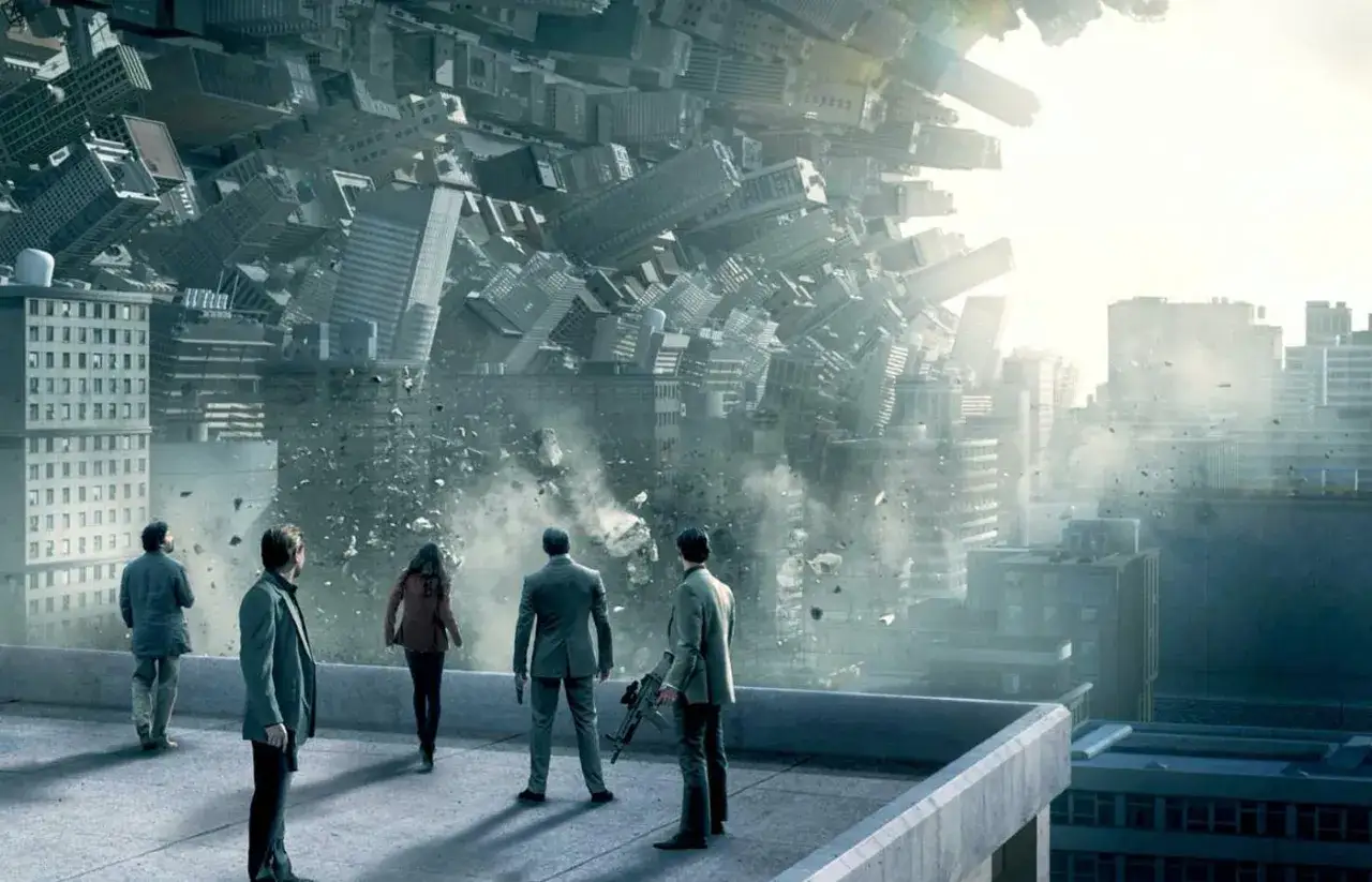 Ludzie na dachu obserwują surrealistyczny krajobraz, gdzie budynki wirują i rozpadają się. To wizja z filmu 