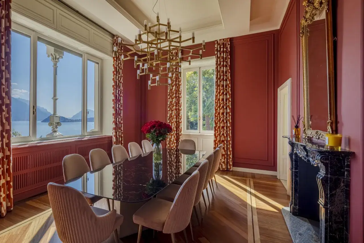 Elegancka jadalnia w stylu art deco, z dużym stołem, aksamitnymi krzesłami i widokiem na jezioro.