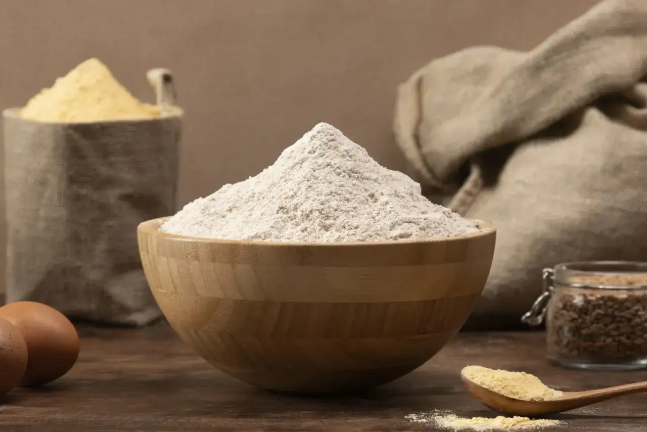 Un bol de farine de gruau, des œufs et des sacs de grains. La farine de gruau, c'est quoi ? Une base pour des recettes rustiques.