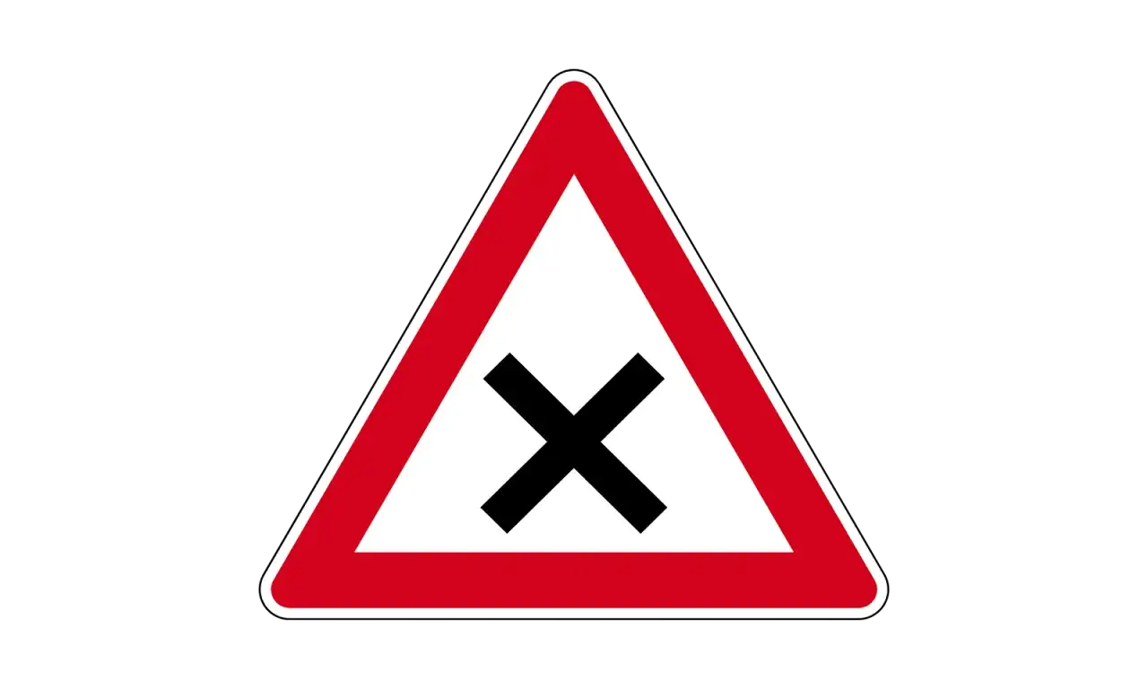 Rotes Dreieck mit schwarzem Kreuz in der Mitte. Dieses Verkehrszeichen warnt vor einer Kreuzung.
