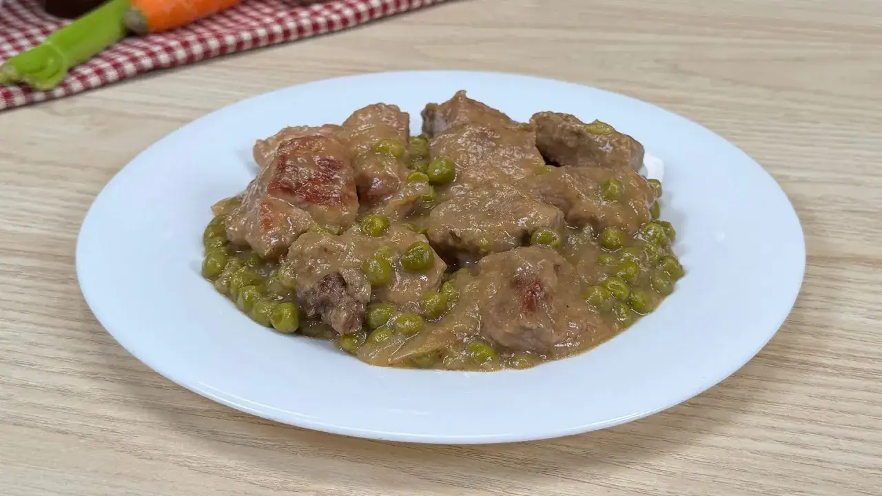 Un saporito spezzatino con piselli, servito su un piatto bianco, pronto per essere gustato.