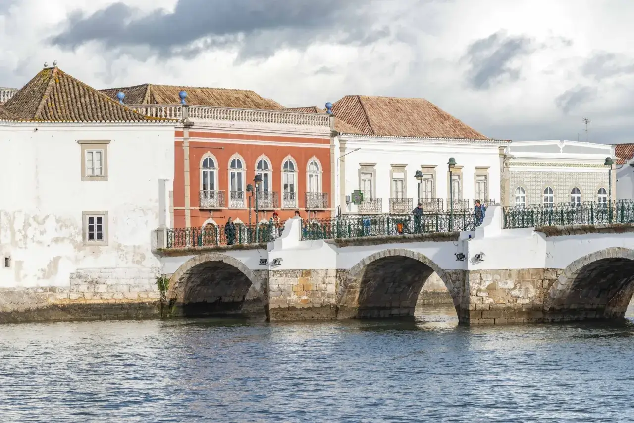 Die Tavira Altstadt mit ihren bunten H&auml;usern und der historischen Br&uuml;cke &uuml;ber den Fluss.