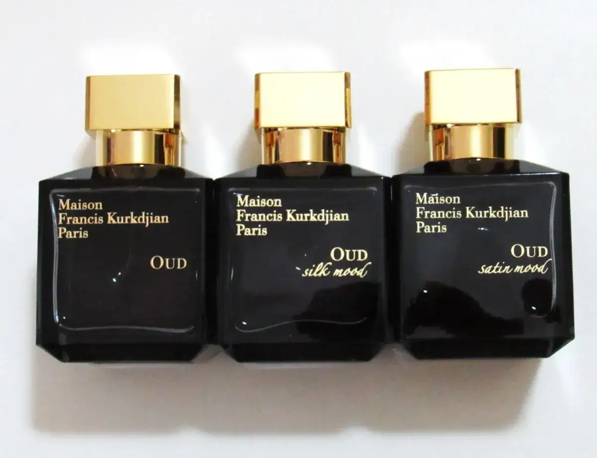 Trzy eleganckie flakony perfum Maison Francis Kurkdjian Oud, Silk Mood i Satin Mood, z złotymi nakrętkami.