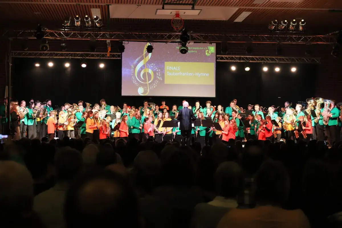 Gro&szlig;es Orchester spielt bei Boxberg Veranstaltungen. Auf der B&uuml;hne stehen Musiker in gr&uuml;nen Jacken, dirigiert von einem Mann im Anzug.