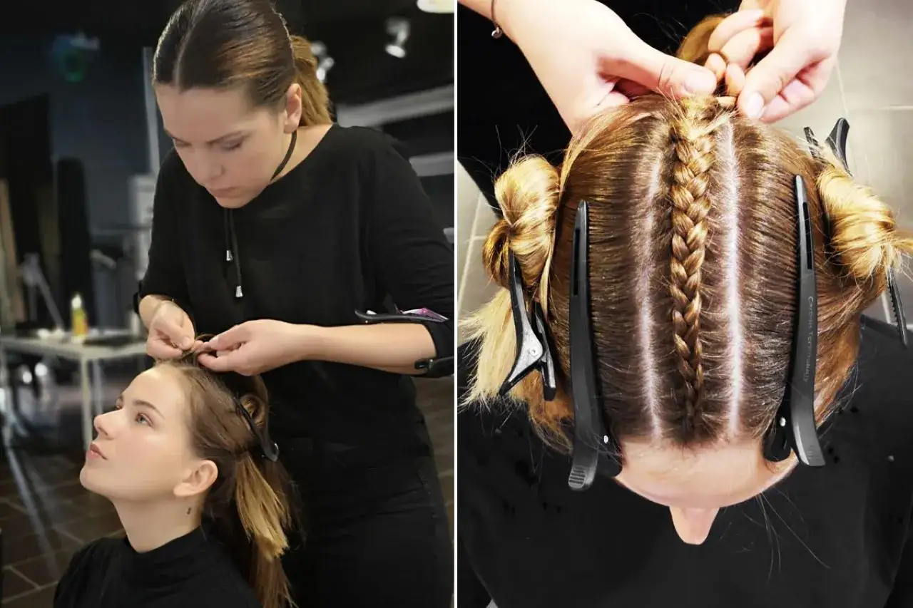 Eine Stylistin flechtet sorgf&auml;ltig die Haare einer jungen Frau. Mehrere Z&ouml;pfe werden auf dem Kopf kreiert, w&auml;hrend die Haare mit Klammern abgeteilt sind.