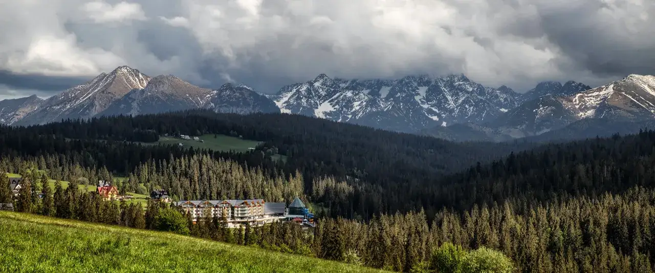 Majestatyczne Tatry nad lasem, gdzie w dole widać Pensjonat u Janeczki w Bukowinie Tatrzańskiej.