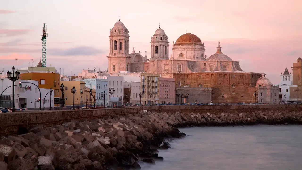 Die Kathedrale von Cadiz ragt majest&auml;tisch &uuml;ber die Stadt und das Meer auf, beleuchtet vom sanften Abendlicht.
