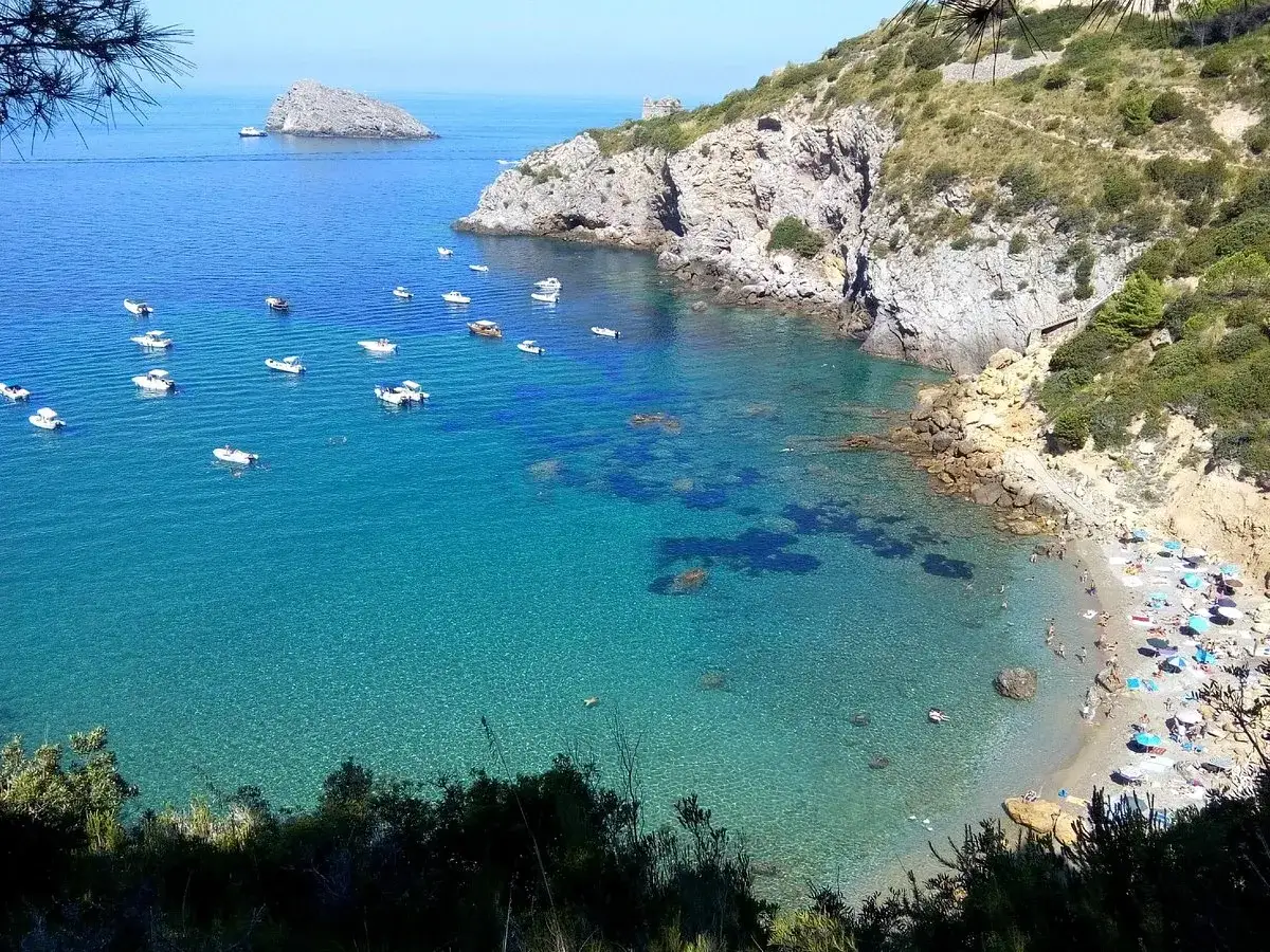 Ein versteckter geheimtipp toskana strand mit kristallklarem Wasser, vielen Booten und einer kleinen Bucht voller Sonnenanbeter.