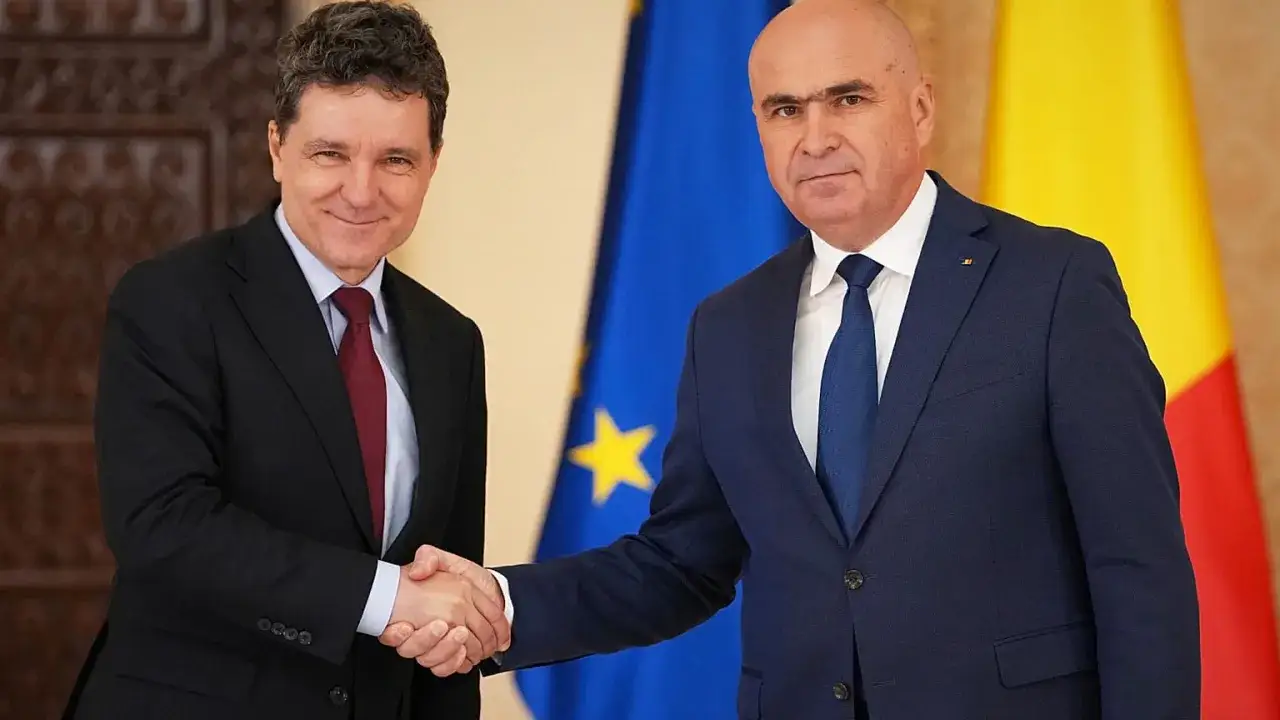 Prezydent Rumunii wita się z delegatem na tle flag UE i Rumunii.