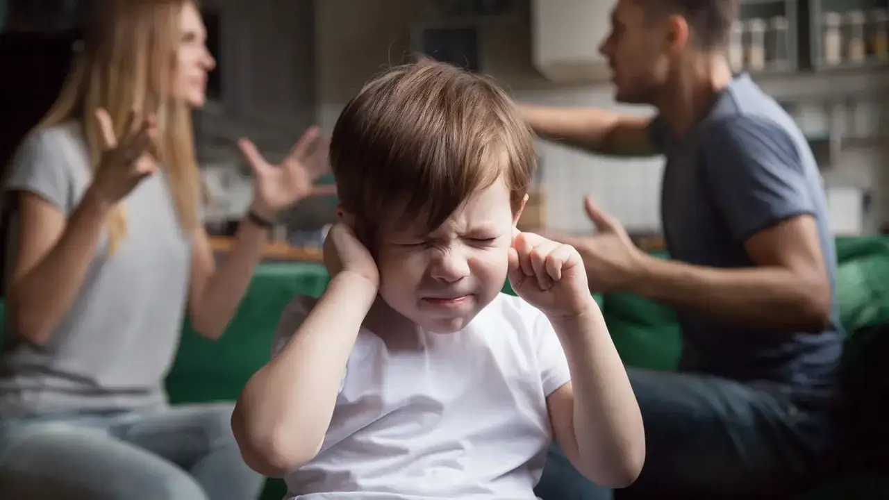 Ni&ntilde;o tapa sus o&iacute;dos mientras sus padres discuten delante de los hijos.