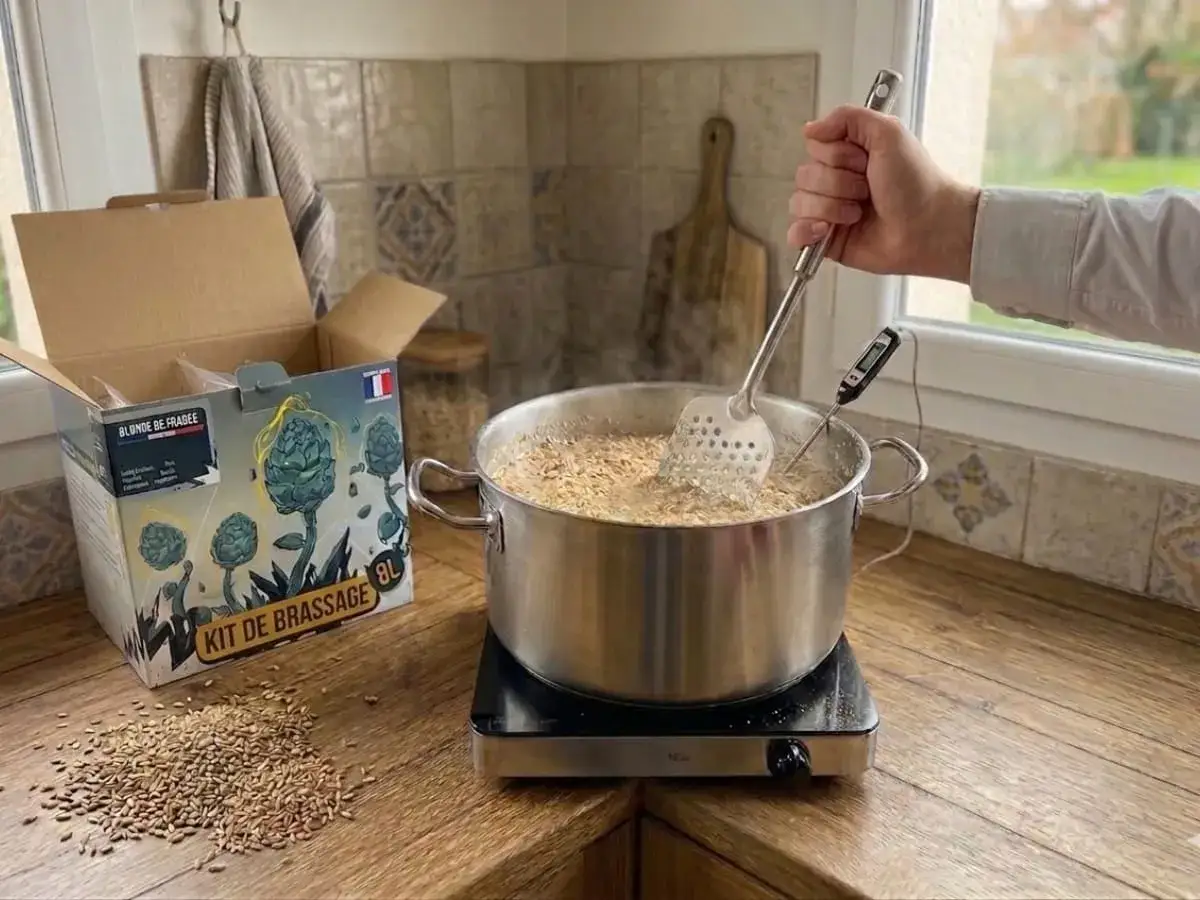 Préparation d'une recette IPA avec un kit de brassage. Une main remue le moût dans une marmite.