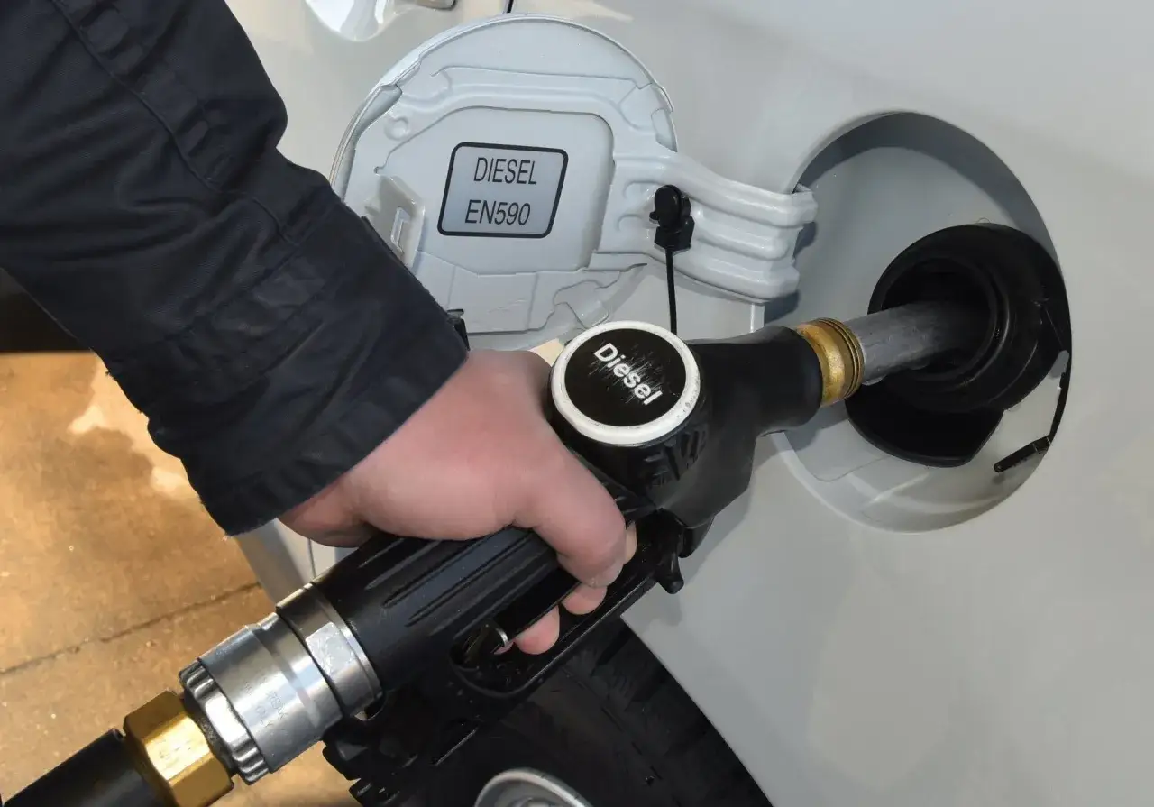 Tankowanie samochodu. Dłoń trzyma pistolet paliwowy z napisem