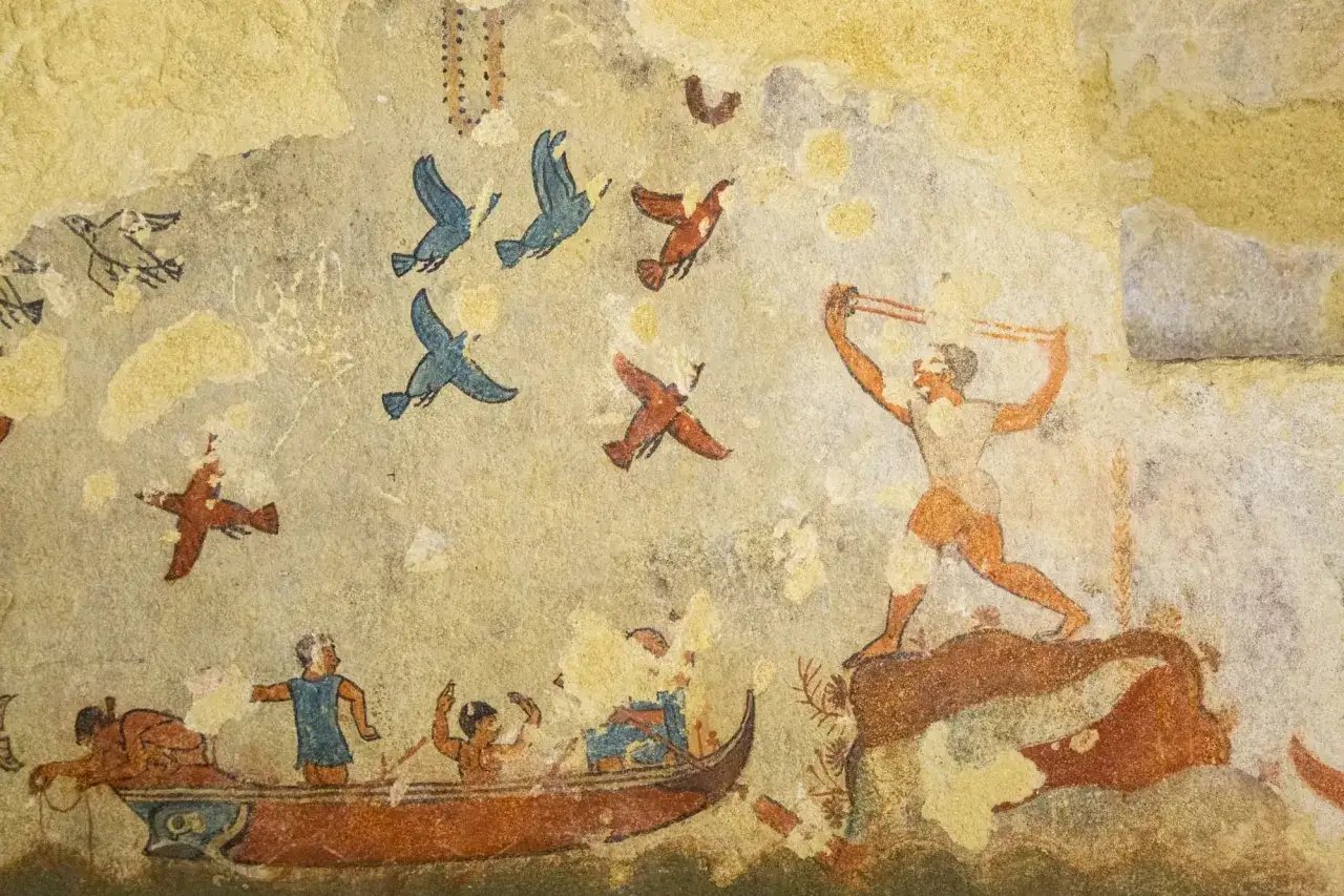 Antica pittura murale da Tarquinia paese: un uomo lancia una fionda, uccelli volano, e una barca con pescatori naviga.