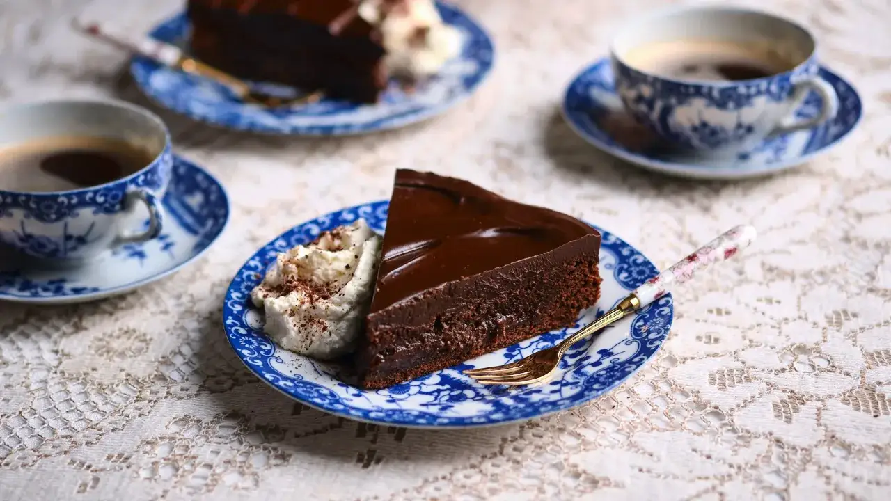 En bit chokladkaka med glansig ganache och vispgr&auml;dde, serverad med kaffe. Perfekt f&ouml;r ett enkelt ganache recept.
