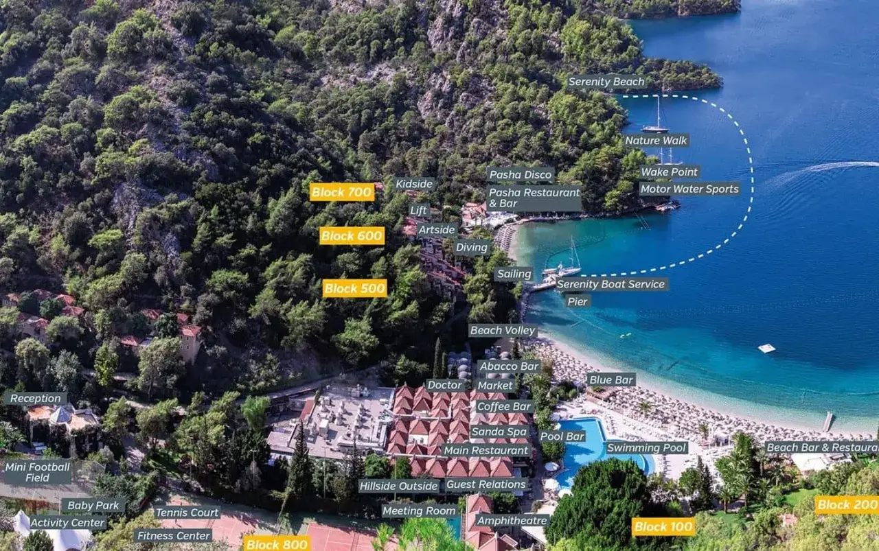 Widok z lotu ptaka na ośrodek z basenami, plażą i budynkami na zboczu wzg&oacute;rza. Oznaczone atrakcje: Serenity Beach, Pasha Restaurant, Serenity Boat Service Pier, baseny, korty tenisowe.