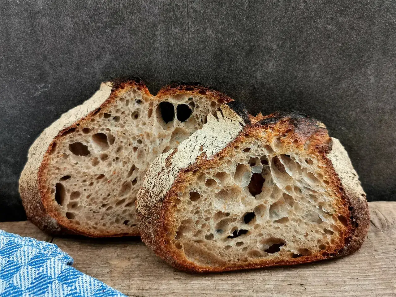Zwei aufgeschnittene Laibe **brot ohne sauerteig** mit knuspriger Kruste und luftiger Krume liegen auf einem Holzbrett.