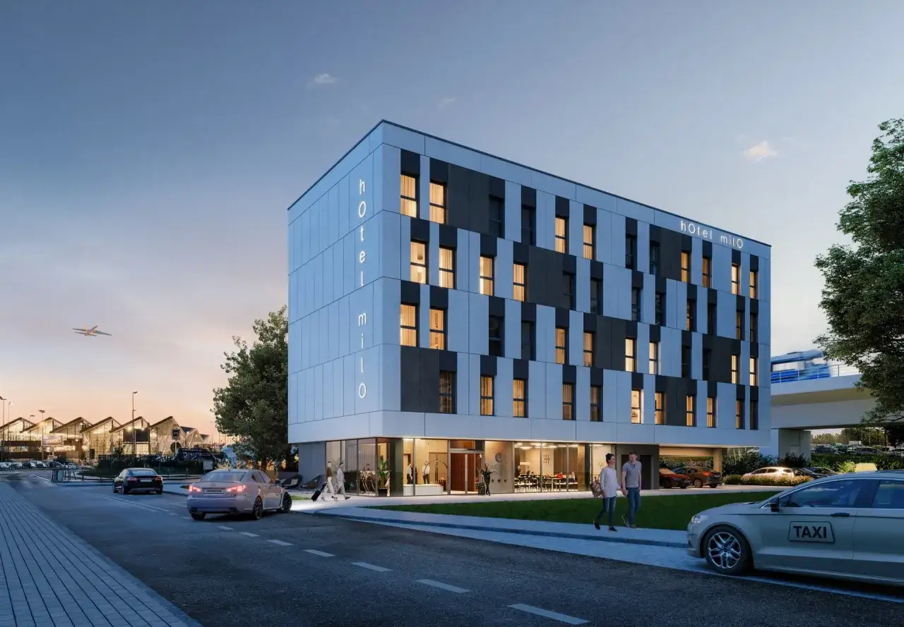 Nowoczesny hotel Milo w dzielnicy gdańskiej z portem lotniczym w tle. Samolot startuje, a przed hotelem parkuje taksówka.