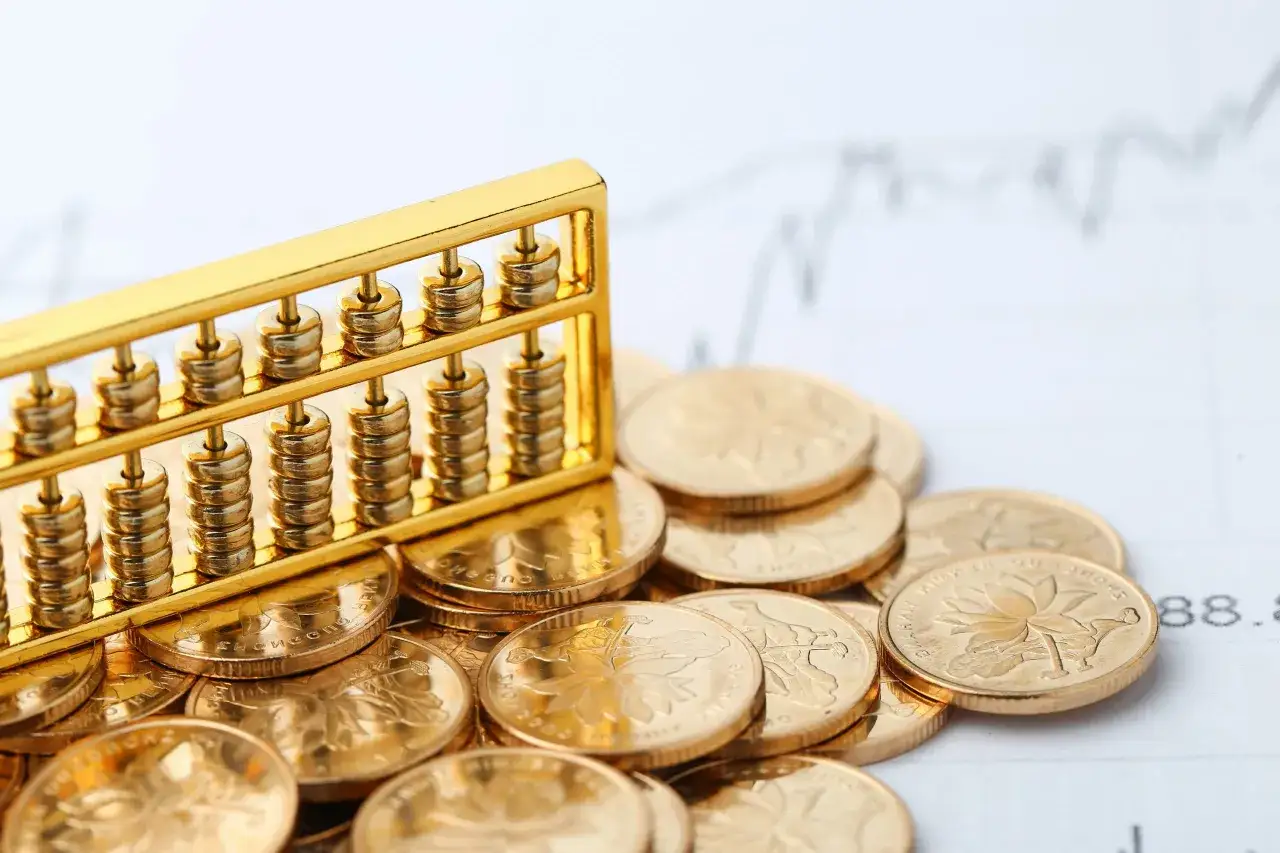 Ábaco dorado sobre monedas, simbolizando el **valor refugio** y la seguridad financiera en un gráfico bursátil.