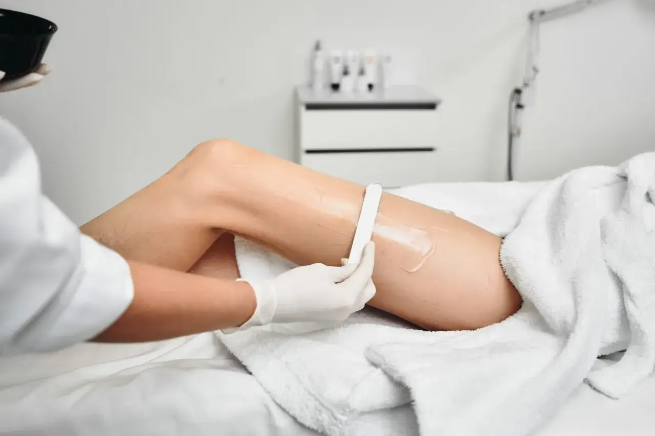 Profesjonalne nakładanie pasty cukrowej do depilacji na nogę za pomocą szpatułki. Dowiedz się, jak używać pasty cukrowej do depilacji.