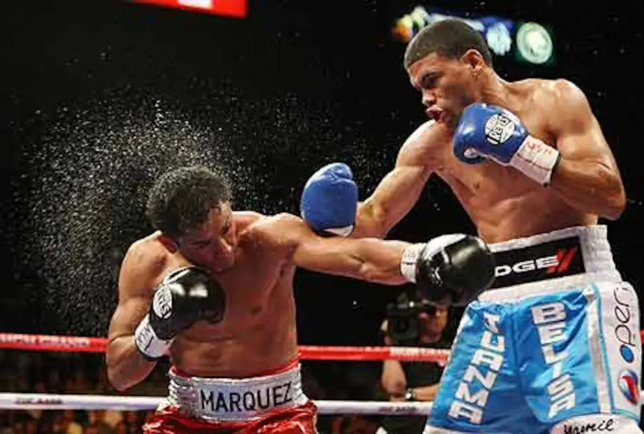 Two boxers, one named Ricardo, exchange blows in a fierce match. Sweat flies as they fight for victory.