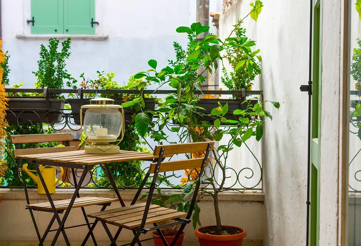 Idéal pour aménager un petit balcon en longueur : une table pliante, deux chaises en bois, une lanterne et de la verdure pour une ambiance cosy.