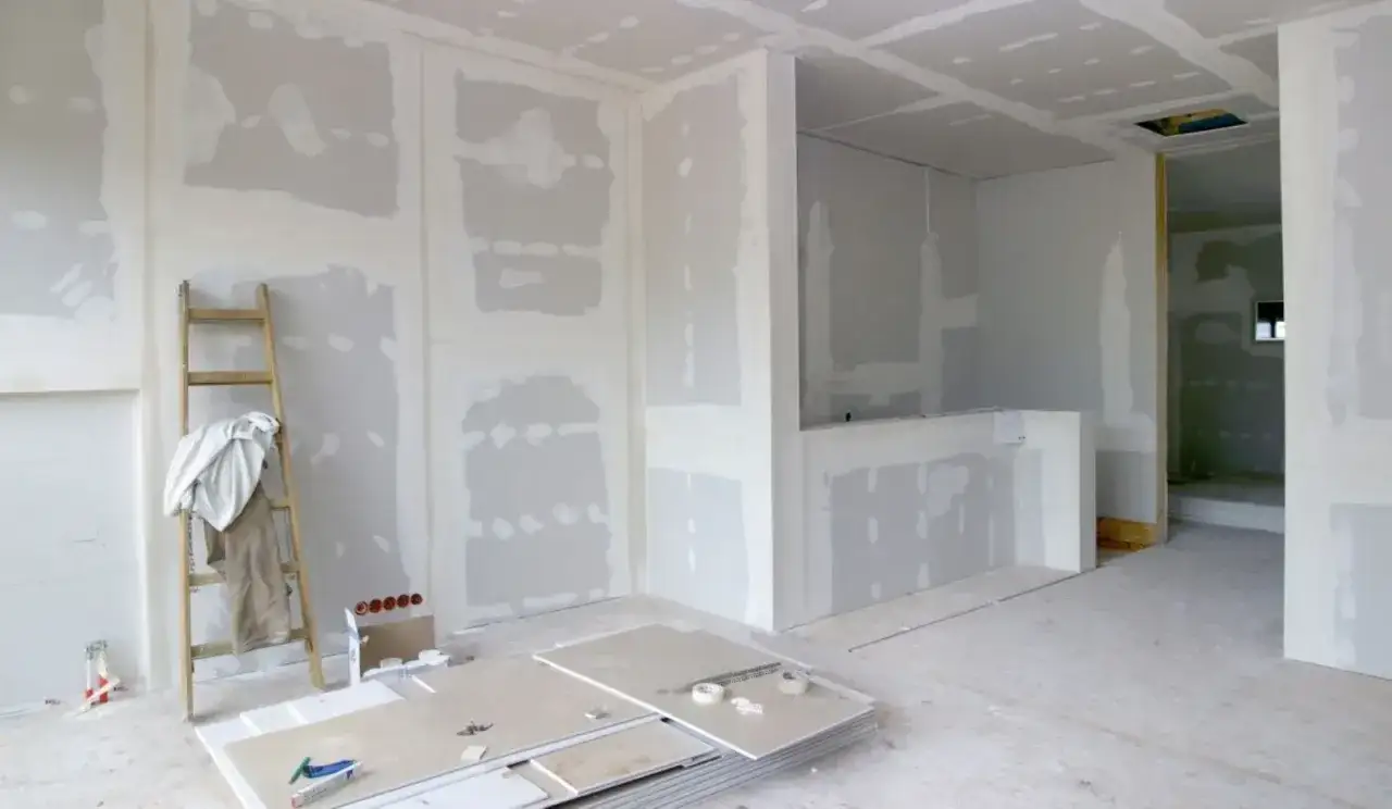 Interno in fase di ristrutturazione con pareti in cartongesso, scala appoggiata e pannelli pronti per il cartongesso fai da te.