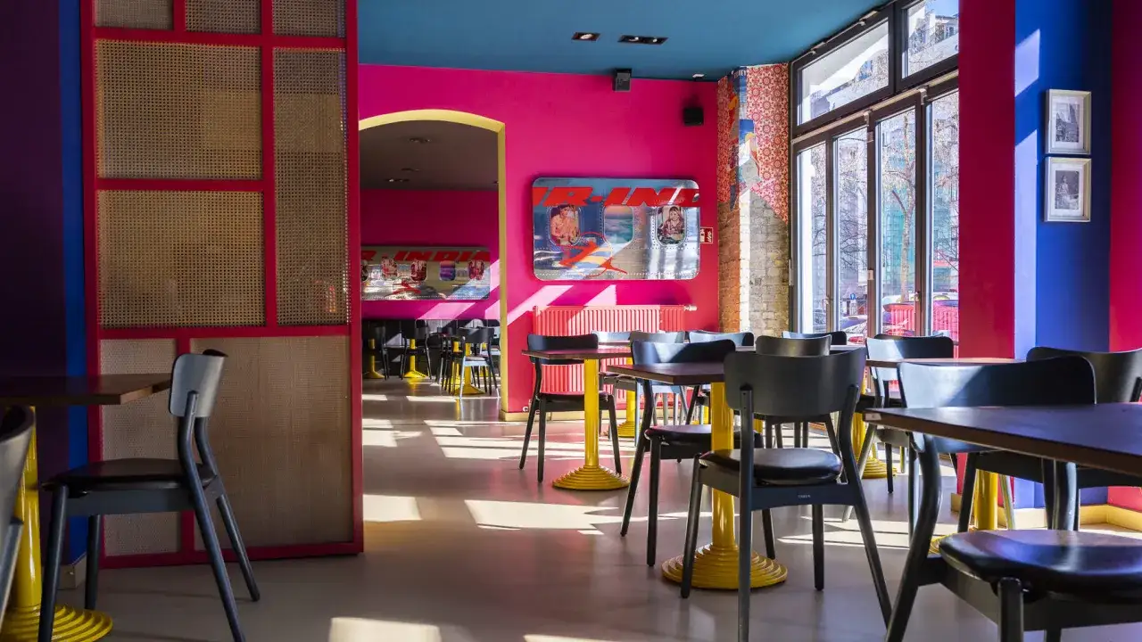 Buntes Restaurant in Berlin mit knallroten W&auml;nden, blauen Decken und gelben Tischf&uuml;&szlig;en. Perfekt f&uuml;r ein farbenfrohes Essen gehen in Berlin.