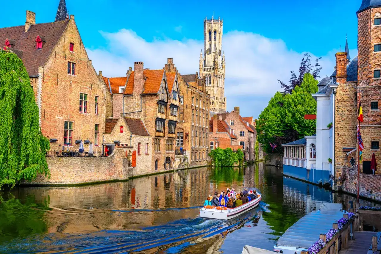 Une balade en bateau sur les canaux, une idée parfaite pour savoir que faire à Bruges. Les maisons historiques et le beffroi se reflètent dans l'eau.