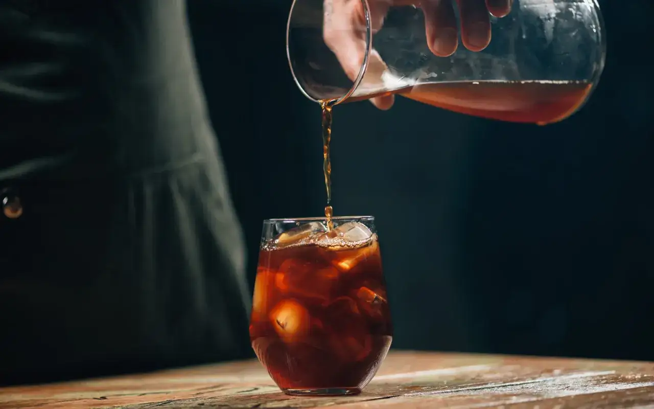 Ein Glas mit Eiswürfeln wird mit kaltem Kaffee aufgefüllt. Ist kalter Kaffee gesund? Ja, er ist erfrischend und belebend.