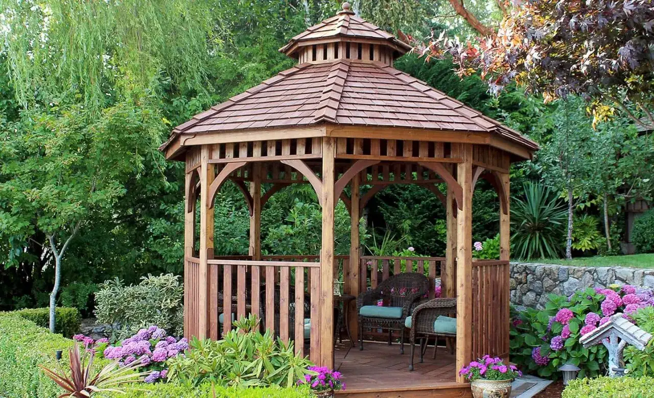 Un incantevole gazebo in legno fai da te, circondato da fiori colorati e vegetazione lussureggiante, offre un rifugio sereno in giardino.