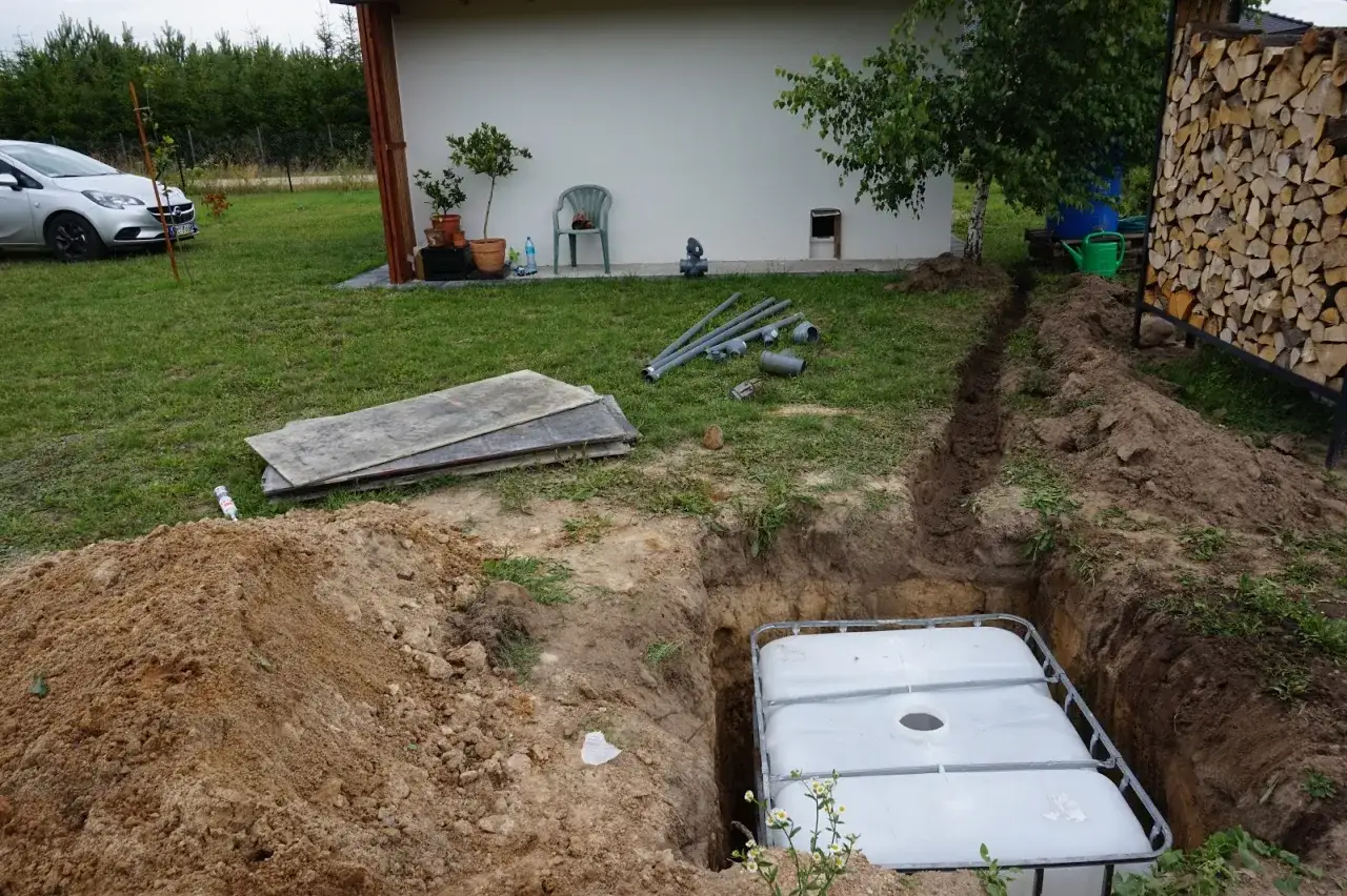 Przygotowania do podłączenia mausera do rynny: wykop, zbiornik IBC, rury i narzędzia.