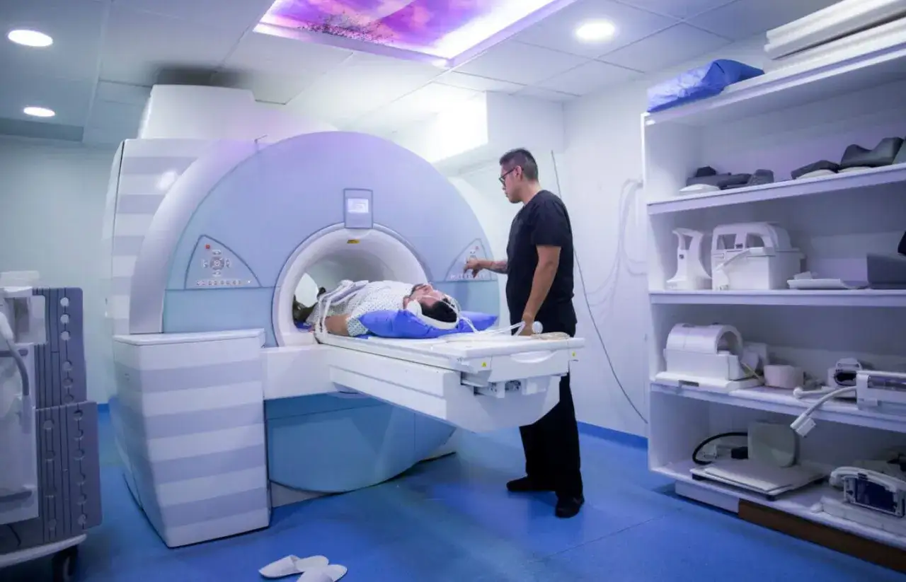 Pacjent leży w aparacie do rezonansu magnetycznego, przygotowując się do badania miednicy. Technik nadzoruje proces.