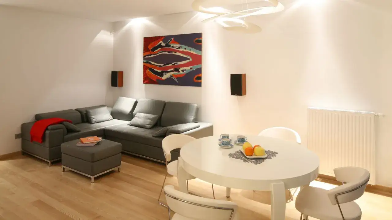 Nowoczesny salon inspiracje: szara kanapa, biały stół z owocami i stylowe dodatki.