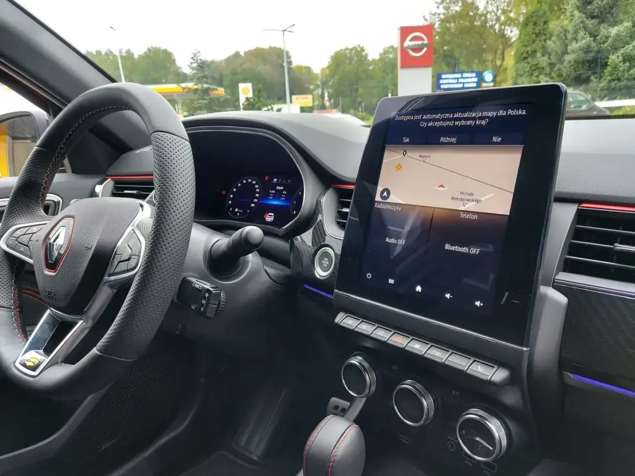 Wnętrze Renault Arkana z nawigacją. Kierownica i ekran multimedialny pokazują aktualizację map. Renault Arkana wymiary są idealne do miasta.
