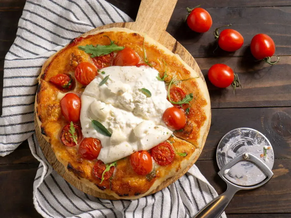 Une d&eacute;licieuse tarte tomate mozza, garnie de tomates cerises r&ocirc;ties et de burrata cr&eacute;meuse, pr&ecirc;te &agrave; &ecirc;tre d&eacute;gust&eacute;e.