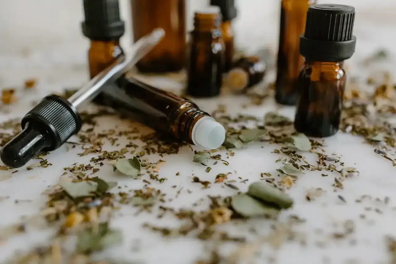 Butelki z edt perfumy i pipetka wśród suszonych ziół. Naturalne składniki do tworzenia własnych zapachów.