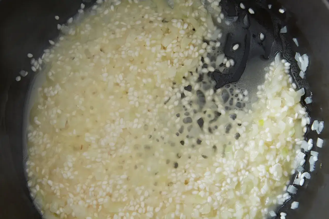 Ryż do risotto smaży się z cebulą na patelni, tworząc kremową bazę do pysznego dania.