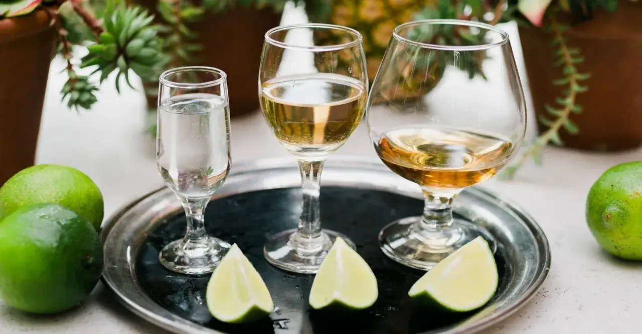 Tequila Silver czy Reposado do Margarity? Trzy kieliszki z tequilą i limonki na tacy.