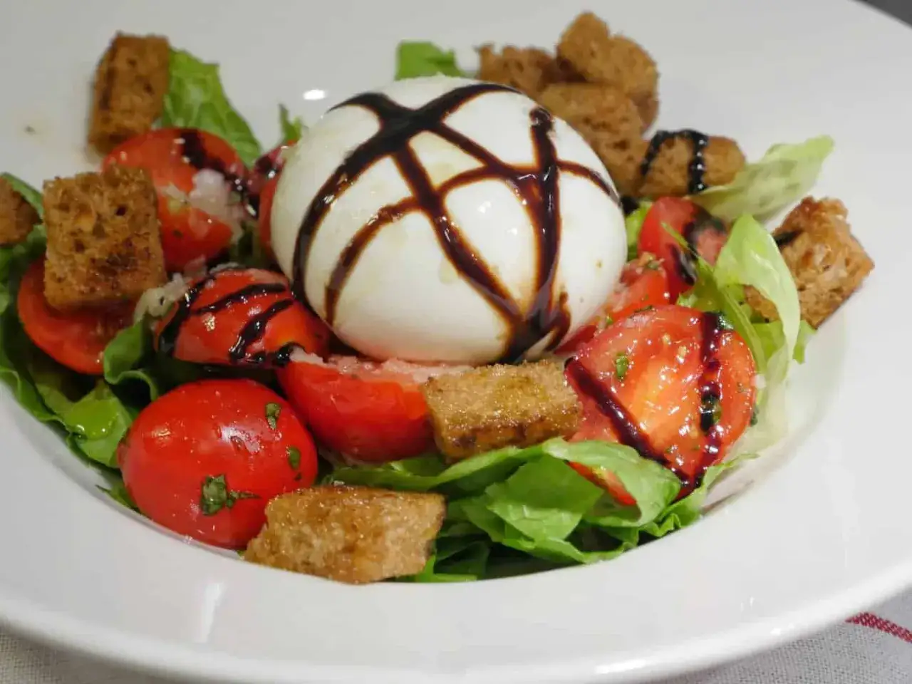 En kr&auml;mig burrata sallad med tomater, krispiga krutonger och en balsamico-glaze.