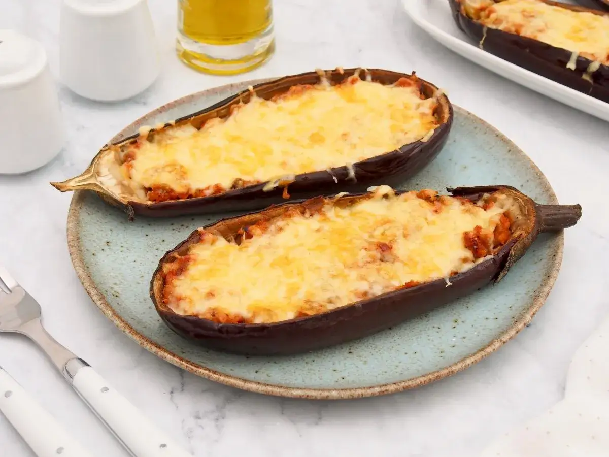 Dos mitades de berenjenas rellenas de at&uacute;n, gratinadas con queso derretido, listas para disfrutar.