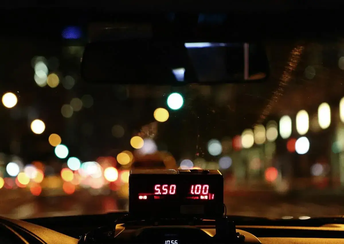 Taxameter zeigt 5.50 an, w&auml;hrend die Lichter der Stadt im Nachttarif vorbeiziehen.