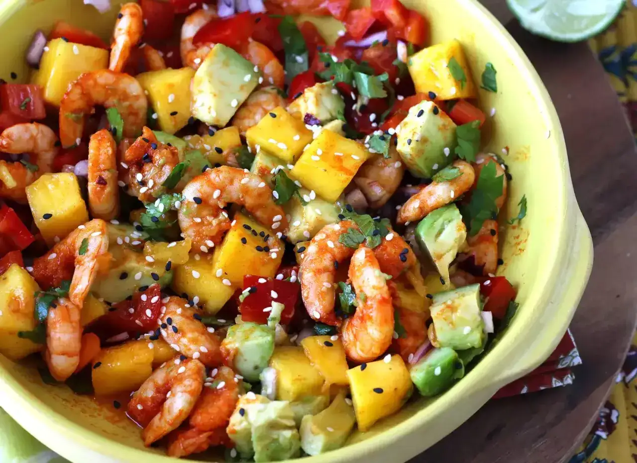 Ensalada de mango con camarones, aguacate y pimientos rojos, espolvoreada con semillas de sésamo.