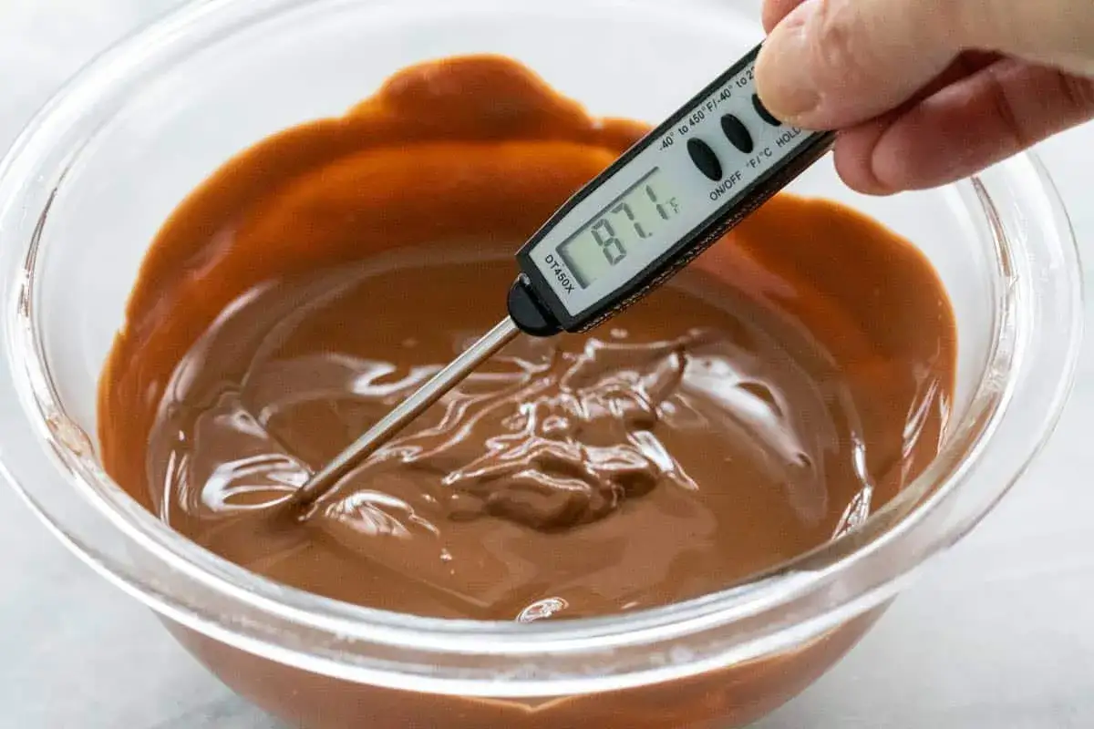 Un thermomètre mesure la température d'un chocolat fondu dans un bol en verre. La température est de 87.1°F. C'est peut-être la raison pour laquelle mon chocolat ne fond pas.