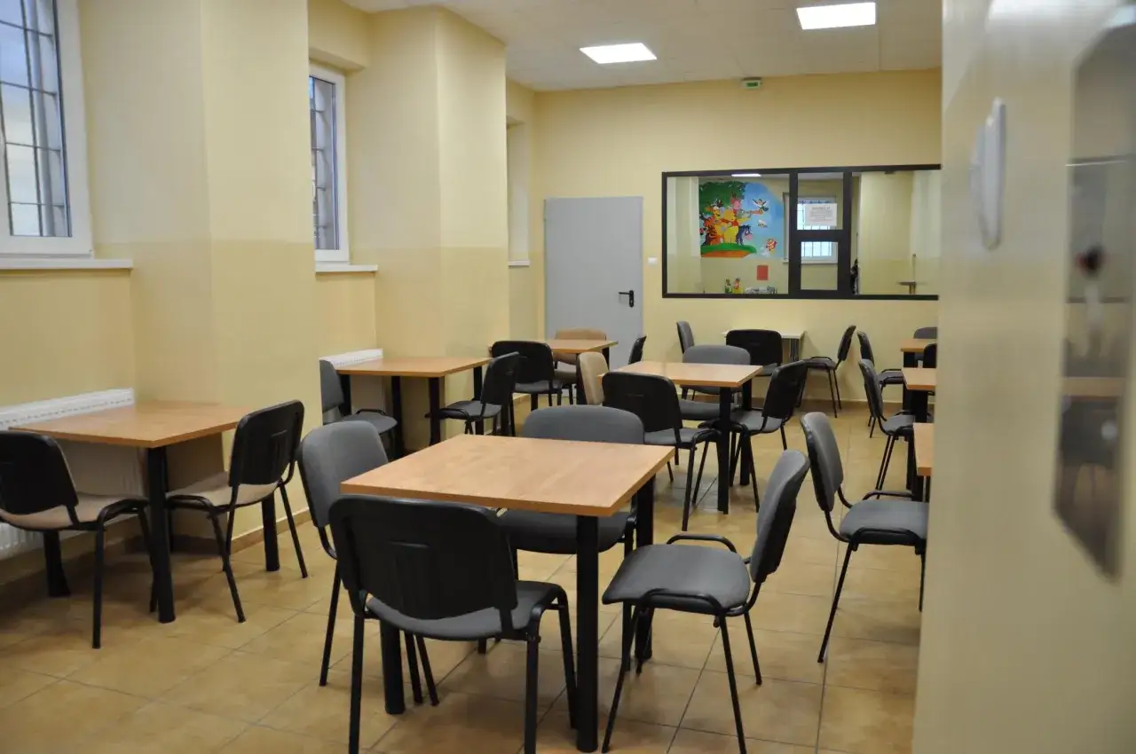 Sala do odwiedzin w zakładzie karnym Montelupich. Puste stoliki i krzesła czekają na gości.