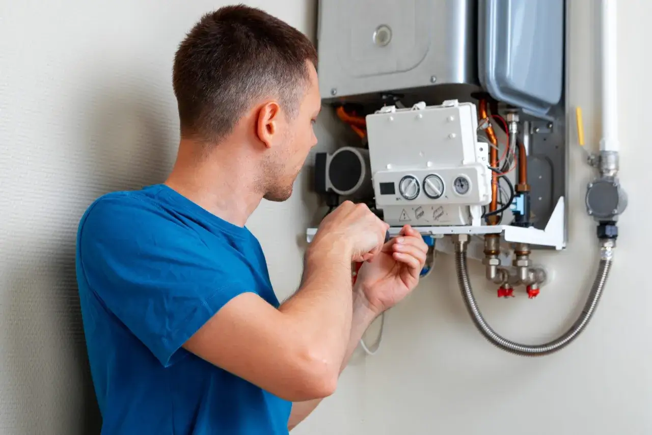 Un technicien effectue le nettoyage de la chaudi&egrave;re &agrave; gaz, v&eacute;rifiant les connexions et les composants pour assurer un fonctionnement optimal.