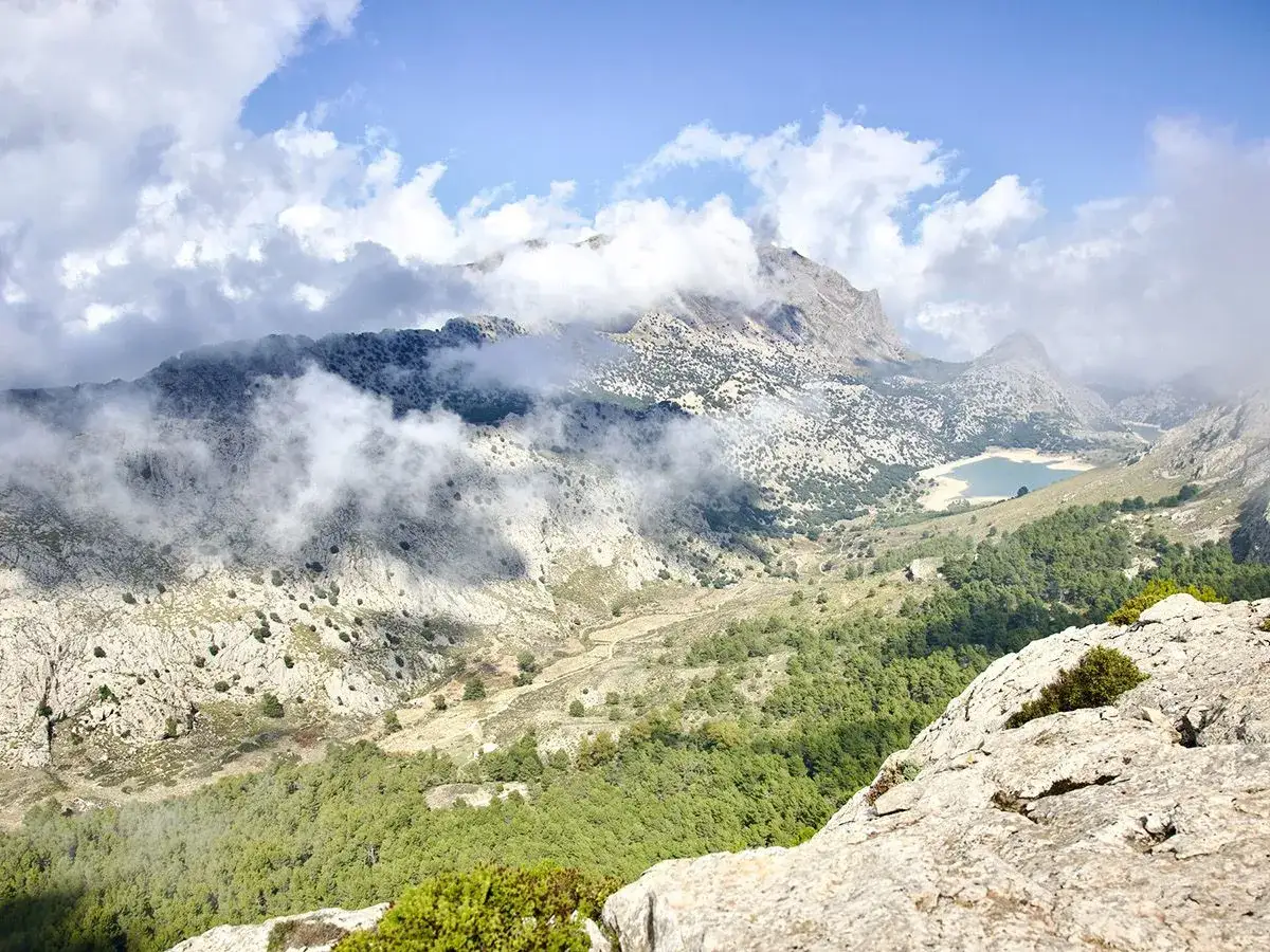 Wolken ziehen über das Tramuntana Gebirge, ein See schimmert in der Ferne.