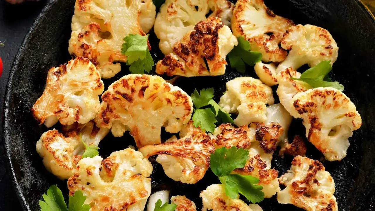 Chou fleur r&ocirc;ti au four, parsem&eacute; de persil frais, pr&eacute;sente des fleurons dor&eacute;s et l&eacute;g&egrave;rement caram&eacute;lis&eacute;s, pr&ecirc;ts &agrave; &ecirc;tre d&eacute;gust&eacute;s.