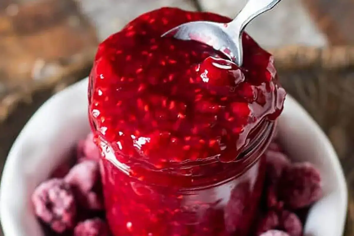 Leckere Himbeersauce aus gefrorenen Himbeeren, die in einem Glas mit einem L&ouml;ffel serviert wird.